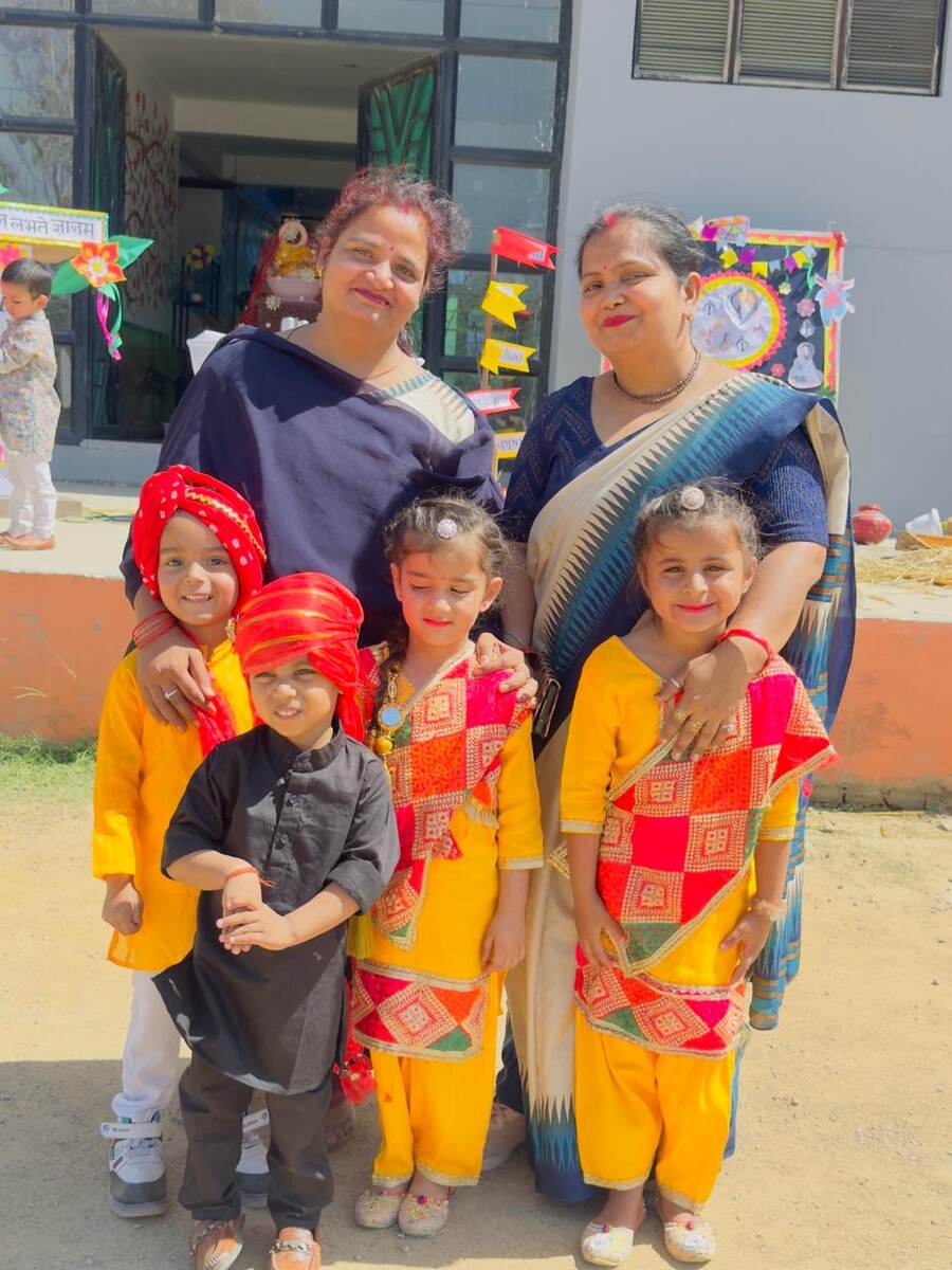 Young students dressed in colourful traditional attire posing with their teachers