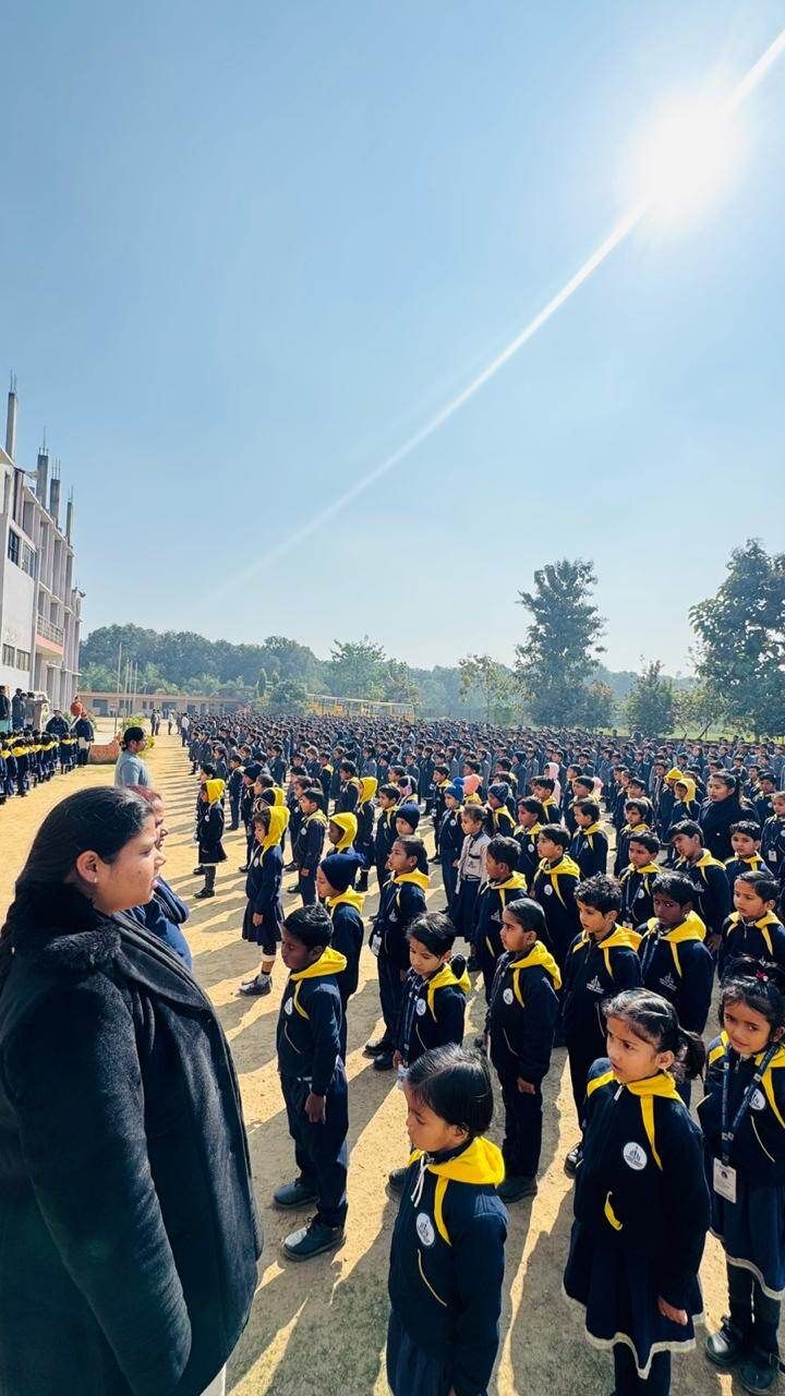 A large gathering of pre-primary students in yellow-hooded uniforms standing in assembly formation on the school ground