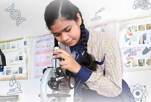 A middle school student examining a specimen through a microscope in the science laboratory